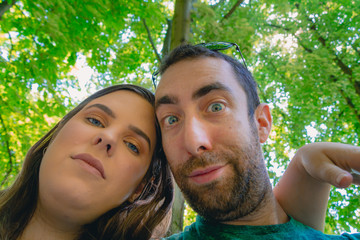 Happy young couple taking a selfie with smartphone or camera at the park