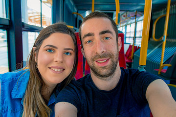 Obraz premium Happy couple taking a selfie with smartphone or camera inside a city bus