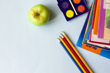 Naklejka premium Pencils, books, color and an apple flat lay