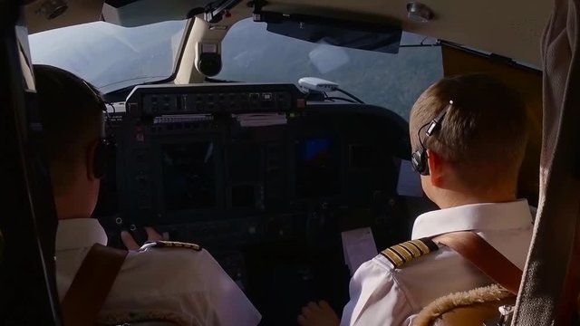 Two pilots having an easy flight over forests and cities, captain controlling flight.