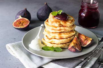 Homemade fluffy pancake with fig jam and fruits decorated with mint and natural yogurt in spoon