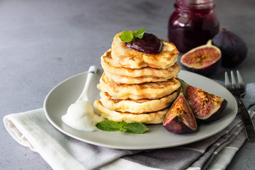 Homemade fluffy pancake with fig jam and fruits decorated with mint and natural yogurt in spoon
