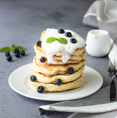 Pancakes with blueberries, greek yogurt and mint leaf on top. 