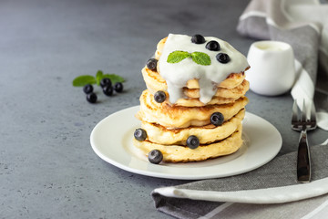 Pancakes with blueberries, greek yogurt and mint leaf on top. 