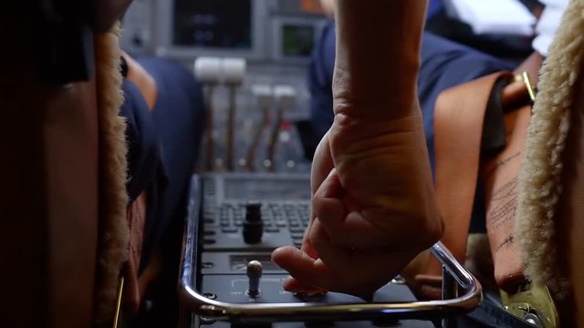 Close-up shot of a pilot pushing buttons on a control panel in cockpit.