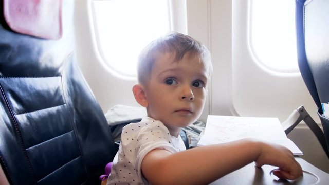 4k video of little toddler boy sitting on passenger seat in airplane during flight