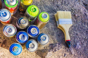 RUSSIA, MOSCOW-JULY 29, 2018: lots of spray cans with graffiti paint standing on the ground and a brush lying next to it. Street art is very popular.