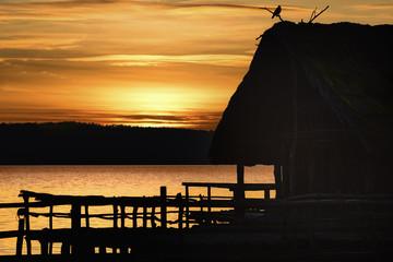Silhouette of a cottage and bird  at sunset