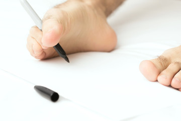 Man writing with right foot on white paper