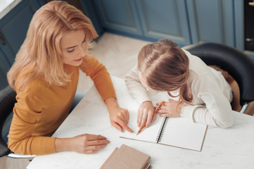 Think a little. Conscious girl sitting at the table and doing her homework