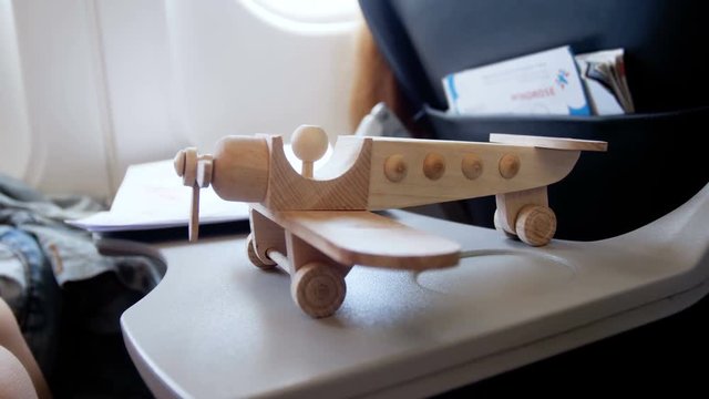 Closeup 4k footage of toy wooden airplane standing on folding table in airplane during flight
