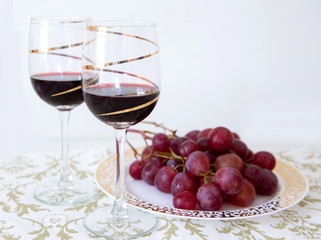 two glasses of red wine with a bunch of red grapes