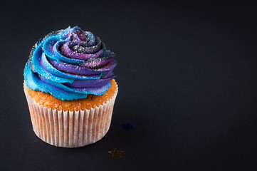 Cupcake with galaxy whipped cream on black background