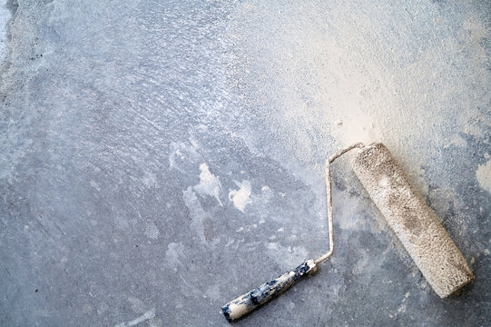 Dirty paint roller on the dirty concrete floor