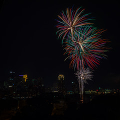 Long exposure of multiple bursts of colorful fireworks  in the sky with a city skyline in the background