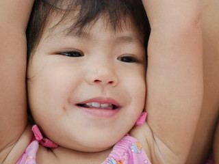 Close up of happy smiling Asian baby girl's face, 18 months old - good mood