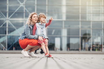 Beautiful Young Mother with Small Stylish Daughter Walks Through City Together