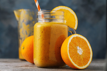 Vitamin drink: smoothies from fresh oranges in a glass jar on a wooden table, close-up
