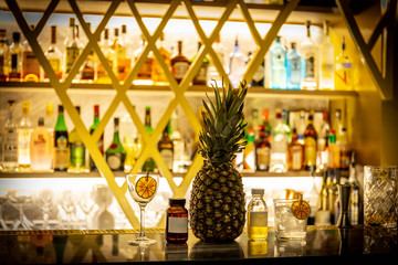 Close up of fruit cocktails standing on the bar with blurry bar environment in the background.