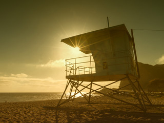 A lifeguard tower often seen along South California Pacific driveway in warm vintage setting