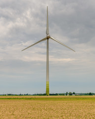Wind Turbine With Motion Blur In An Empty Field Under A Cloudy Grey Sky