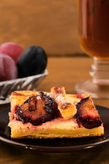 Portion of homemade cake with plums on a plate, close-up, vertical frame.