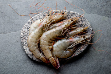 Raw whole fresh uncooked prawns shrimps on stone gray plate, stone background. Top view with copy space