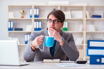 Businessman chained with handcuffs to his coffee