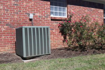 Air conditioner unit at a home with rose bushes