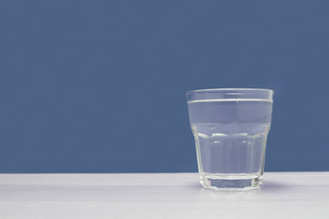 Clear glass of water against empty blue background