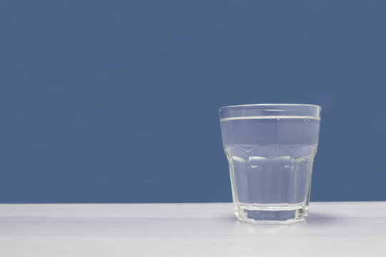 Clear Glass Of Water Against Empty Blue Background