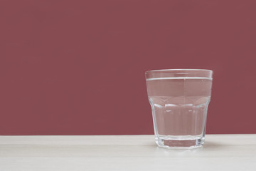 Clear glass of water against empty blue background