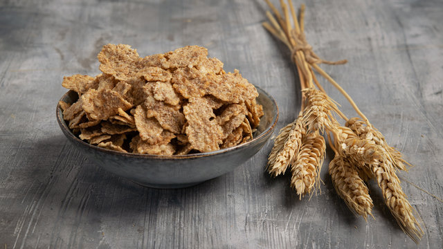 Multigrain wholewheat healthy cereals in ceramic bowl and golden wheat ears on gray background banner.