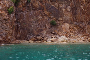 Fototapeta na wymiar turquise ocean water next to red rock formation