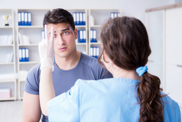 Fototapeta premium Young man visiting female traumatologist with black eye 