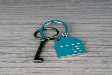 key and house shape key tag on wooden table. home security and buying house concept