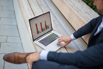 Handsome young businessman working outside on his laptop