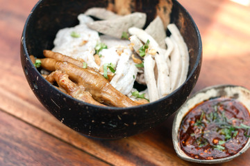 Vietnamese rice noodle soup with sliced ​​pork and chicken feet spicy soup in bowl made of coconut shell with sauce, Traditional food of Vietnamese.