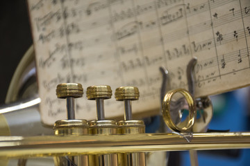 Obraz premium Detail of a trombone's pistons and music sheet in the background