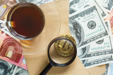  Bitcoins through magnifying glass on the real money background. Investment, risk, business strategy