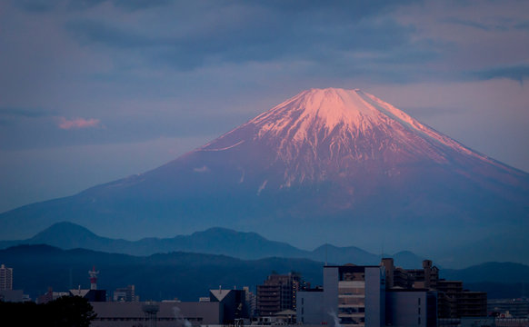 Morning light illuminating the peak of mount Fuji in the background of a small city