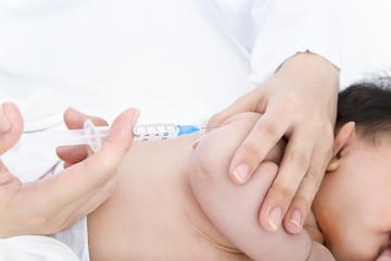 Obraz na płótnie Canvas 医師(看護師)により腕に注射を打たれ泣いている新生児の赤ちゃん。予防接種、インフルエンザ、病気、治療イメージ