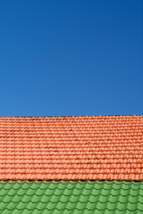 Multicolored tiled roofs of houses against the blue sky with clouds Background Attics Orange and green color Vertical