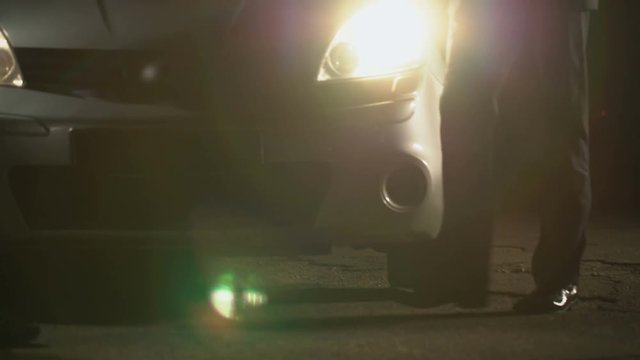 Male in suit giving photo of future victim to contract killer near car at night