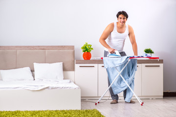 Young man ironing in the bedroom 