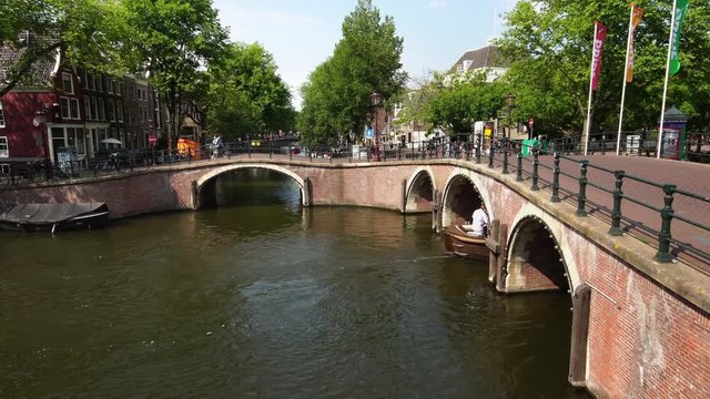 Traditional boat in Amsterdam canal on sunny day in Netherlands