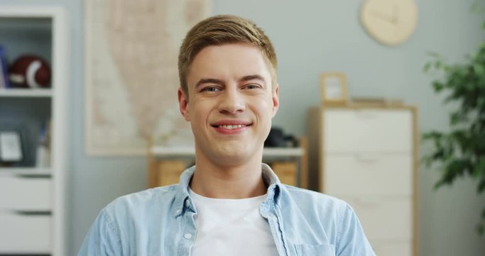 Portrait of the handsome Caucasian young man turning his head and smiling to the camera.
