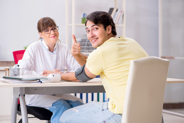 Obraz premium Young doctor checking patients blood pressure