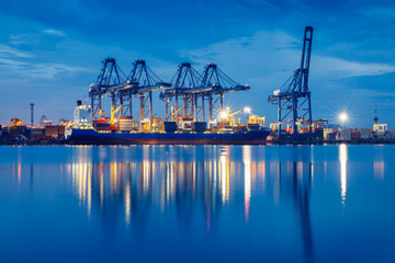 Containers loading by crane in the evening trade port shipping, Shipping and logistic concept