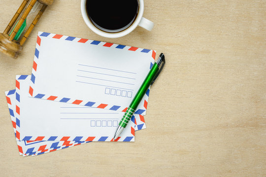 Table top view aerial image of business office desk background concept.Flat lay object ongoing write envelope by pen with black coffee on modern rustic brown wooden.Copy space for creative design text